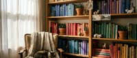 Cozy reading corner with wooden bookshelf filled with colorful books, comfortable armchair with knitted throw blanket, and small potted plants creating warm home library atmosphere.