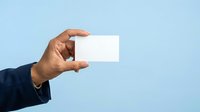 Man holding blank white business card against light blue background, ready for branding and corporate identity design projects.