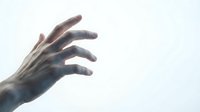 Zombie hand reaching upward against pale sky background for horror themed designs and Halloween projects.