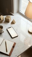 Smartphone mockup on marble desk with wooden geometric shapes, notebook and coffee cup in warm natural light for branding and app presentation.