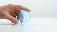 Hand holding glowing blue sphere with wheelchair accessibility symbol for disability support, inclusive services, healthcare assistance, and social responsibility concepts.