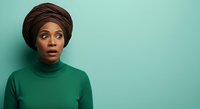Woman with dark skin tone wearing green turtleneck and brown head wrap against turquoise background, expressing surprise or concern, suitable for portrait and lifestyle content.