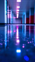 Empty corridor with neon pink and blue lights reflecting on wet floor surface creating dramatic perspective and bokeh effect. Modern interior lighting design.