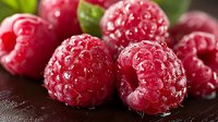 Fresh ripe raspberries with water drops on dark background, macro shot showing detailed texture and natural juicy appearance of organic berries.
