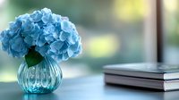 Blue hydrangea flowers in glass vase on table with books creating elegant home decor arrangement for interior design and lifestyle photography.