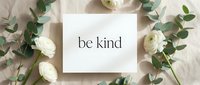 Be kind motivational quote card surrounded by white ranunculus flowers and eucalyptus on a neutral linen background, flat lay style.