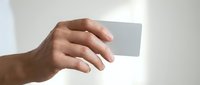 Hand holding blank white business card mockup against neutral background for branding and corporate identity design projects.