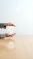 Businessman hands protecting glowing lightbulb on wooden desk symbolizing innovation protection, creative ideas security, intellectual property concept.