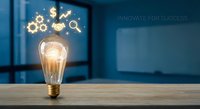 Glowing light bulb with innovation icons on wooden desk representing creative business ideas and entrepreneurial success in modern office environment.
