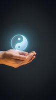 Hand holding glowing yin yang symbol against dark background, representing balance, harmony, spirituality, and wellness concepts for meditation and alternative healing practices.
