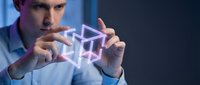 Man in light blue shirt holding glowing geometric holographic cube symbol, representing digital technology, innovation, and futuristic business solutions for corporate design.