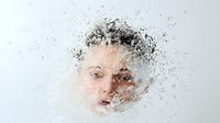 Young Caucasian woman's face behind frosted glass with water drops and condensation creating dreamy, ethereal atmosphere. Artistic portrait showing mystery and contemplation.