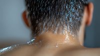 Close-up view of wet male neck and hair with water droplets against blurred background, showing freshness and hygiene concept after shower or workout.