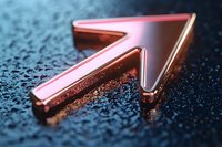Metallic rose gold arrow pointing upward on dark textured background with water drops, symbolizing growth, success and forward movement in business.