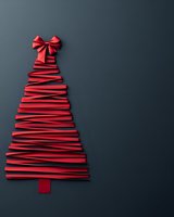 Red paper strips arranged as Christmas tree with bow on dark background for holiday greeting cards and seasonal decorations.
