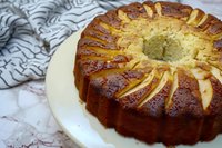 Homemade apple bundt cake with golden brown crust and sliced apples arranged in decorative pattern on white plate ready for dessert serving.