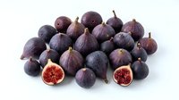 Fresh ripe figs pile with cut halves showing red flesh interior isolated on white background for healthy eating and Mediterranean cuisine recipes.