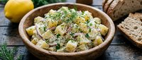 Creamy potato salad with fresh dill and herbs served in wooden bowl, ready for lunch or dinner meal preparation and catering.