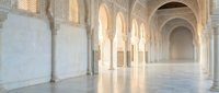 Elegant Islamic architecture interior with ornate arches, marble columns and warm sunlight streaming through traditional geometric patterns creating peaceful atmosphere.
