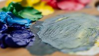 Colorful oil paint palette with mixed colors on wooden surface for artistic creativity and painting projects.
