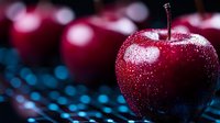 Fresh red apple with water drops on dark background with bokeh lights, macro photography showing detailed texture and reflective surface.
