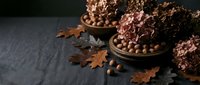 Autumn still life with dried hydrangea flowers, acorns and oak leaves in rustic bowls on dark slate surface for seasonal home decor and fall crafting projects.
