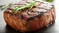 Grilled beef steak with fresh rosemary herbs on dark slate surface. Juicy cooked meat with grill marks for restaurant menu, cooking blog, food photography.