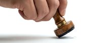 Hand pressing a wooden rubber stamp on white background, approval and certification concept for business and legal documents.