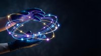 Futuristic holographic interface with glowing blue light trails and energy rings floating above human hands in dark space for technology concepts.