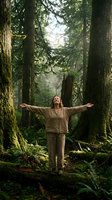 Woman with arms outstretched embracing nature in lush green forest. Peaceful moment of connection with wilderness and personal freedom in natural environment.