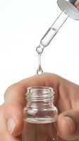 Dropper releasing a clear serum drop into a glass bottle held by hand, skincare routine concept for beauty and wellness brands.
