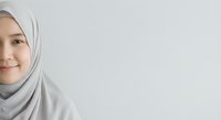 Young Muslim woman wearing light gray hijab smiling gently against neutral background. Professional portrait for diversity and inclusion content.