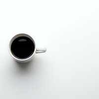 White coffee cup with black coffee on clean white background for minimalist design projects and cafe branding materials.
