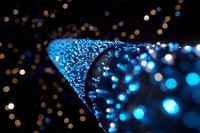 Glowing blue fiber optic lights creating spiral pattern against dark background with golden bokeh effect, modern technology and communication concept.