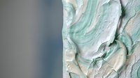 Mint green and white swirled frosting texture with smooth creamy peaks and valleys creating an elegant dessert background for culinary designs.