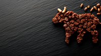 Moose silhouette made from chocolate cookie crumbs and almonds on dark slate background, creative food photography for restaurant menu design.
