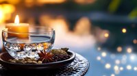 Cozy evening scene with lit candle and glass cup on decorative plate with coffee beans and star anise spice creating warm atmospheric lighting for relaxation.
