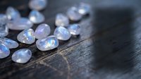 Sparkling clear gemstones scattered on dark wooden surface with rainbow reflections creating luxury jewelry and precious stone concept for design projects.