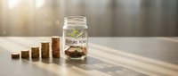 Glass jar labeled future fund with cannabis leaf symbol and coins stacked beside it representing marijuana investment savings and financial planning.