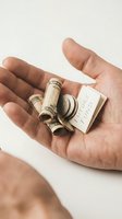 Close-up of male hand holding rolled dollar bills with rubber band and save funds note on white background for financial planning concepts.