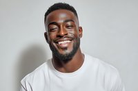Happy young African American man smiling broadly in white t-shirt against neutral background for lifestyle and portrait photography projects.