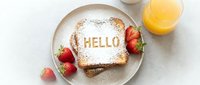 French toast with powdered sugar spelling HELLO on a plate, served with fresh strawberries and orange juice, top view breakfast scene.