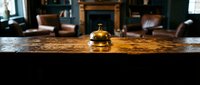 Vintage brass service bell on a rustic wooden hotel reception desk with elegant lobby interior in the background.
