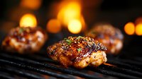 Juicy grilled chicken thighs with caramelized glaze and herbs cooking on barbecue grill with flames and bokeh lights in background. Food photography.