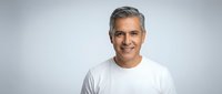 Confident mature Caucasian businessman with gray hair wearing white shirt smiling at camera on neutral background for professional headshot portraits.