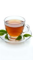 Glass cup of hot tea with green leaves on saucer isolated on white background for beverage and wellness designs.