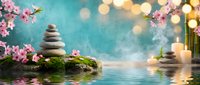 Zen spa composition with balanced stone cairns, pink cherry blossoms, candles and soft bokeh lights reflecting on calm water for meditation and wellness.