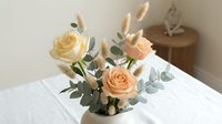 Elegant peach and cream roses with eucalyptus leaves in modern floral arrangement on white table for home decor and interior design projects.