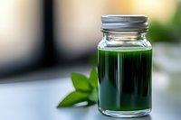 Fresh green juice in glass mason jar with metal lid and green leaves on blurred kitchen background for healthy lifestyle and detox concepts.