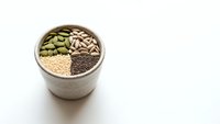 Assorted seeds and grains in wooden bowl including pumpkin seeds, sunflower seeds, quinoa and chia seeds for healthy cooking and nutrition.